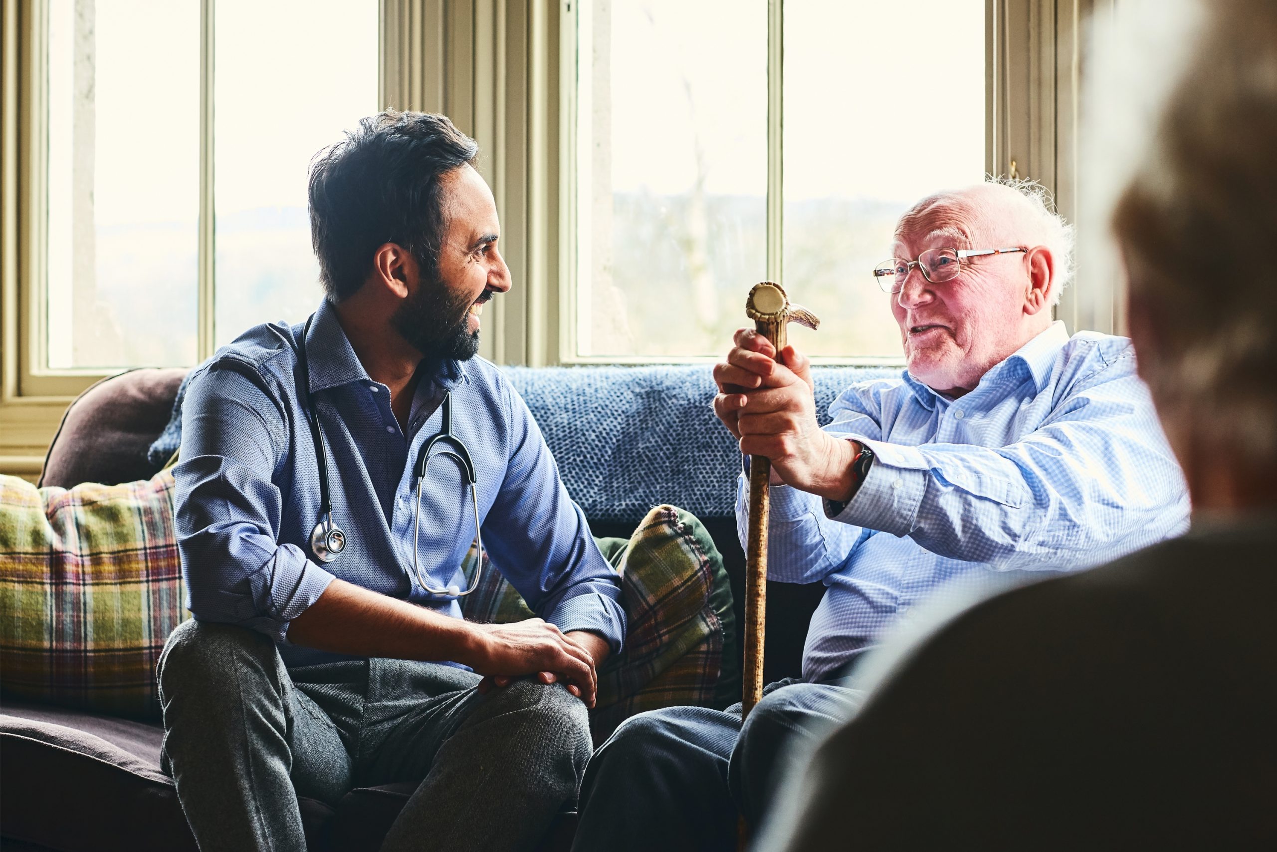 Smiling doctor visiting senior man at home Pflegeberatung – Eldercare